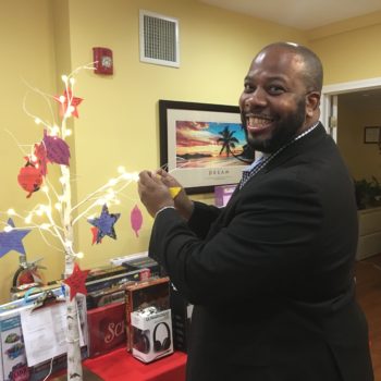 Freeholder Kenneth Armwood, a volunteer and supporter of Women Aware since 1995, hangs a client ornament